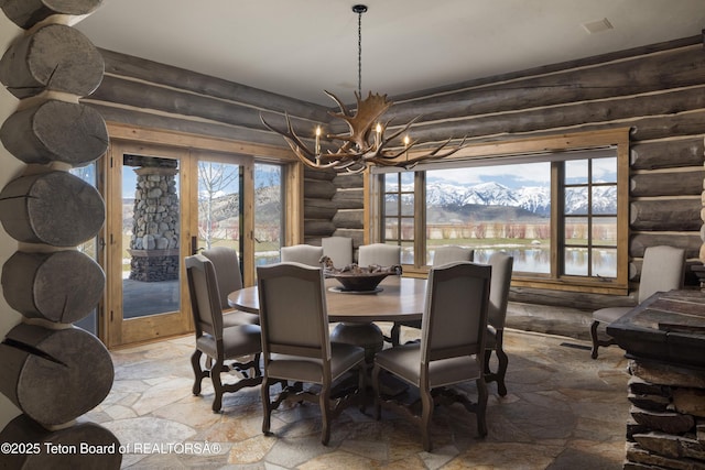 dining space featuring a mountain view, french doors, rustic walls, and a chandelier