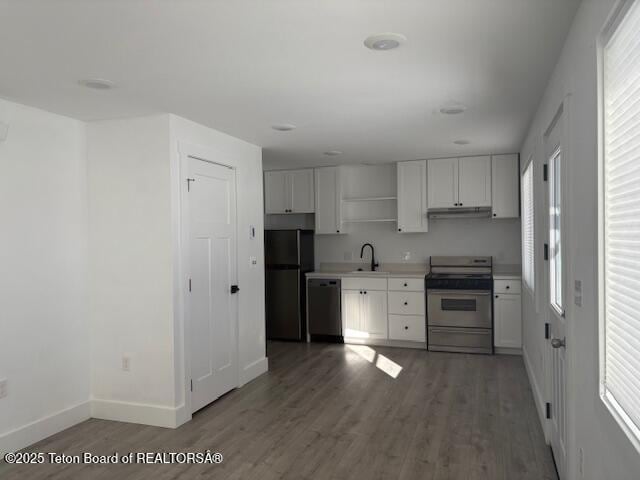 kitchen featuring appliances with stainless steel finishes, dark wood-type flooring, sink, and white cabinets