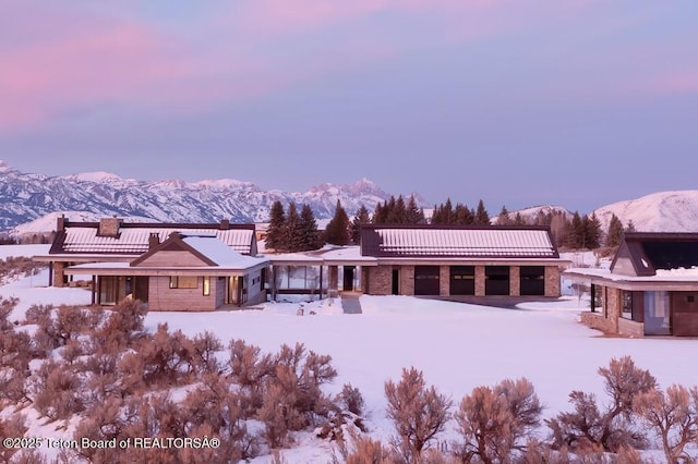 snow covered rear of property with a mountain view