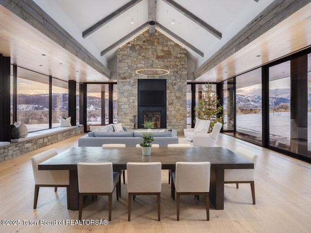 dining area featuring high vaulted ceiling, beamed ceiling, and light wood-type flooring