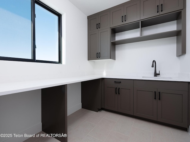 kitchen featuring light tile patterned flooring, dark brown cabinetry, and sink