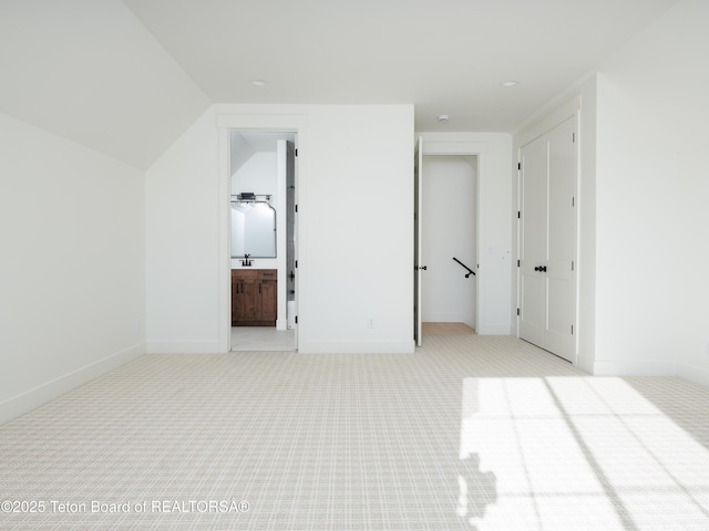 unfurnished bedroom with lofted ceiling, sink, and light colored carpet