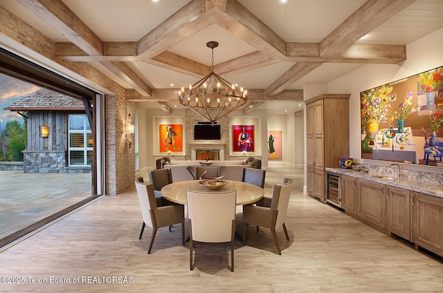 dining space featuring wine cooler, sink, a fireplace, and light hardwood / wood-style floors