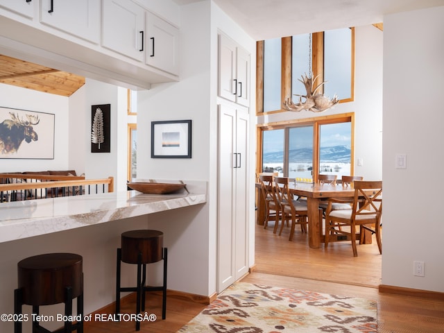 kitchen with light stone countertops, white cabinets, a mountain view, and light hardwood / wood-style flooring