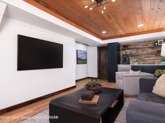 living room with a raised ceiling, light wood-type flooring, and wooden ceiling