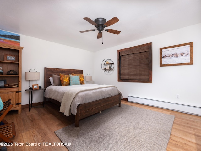 bedroom featuring a baseboard heating unit, hardwood / wood-style flooring, and ceiling fan