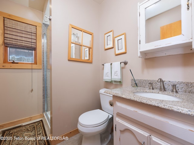 bathroom featuring vanity, toilet, and a shower with shower door