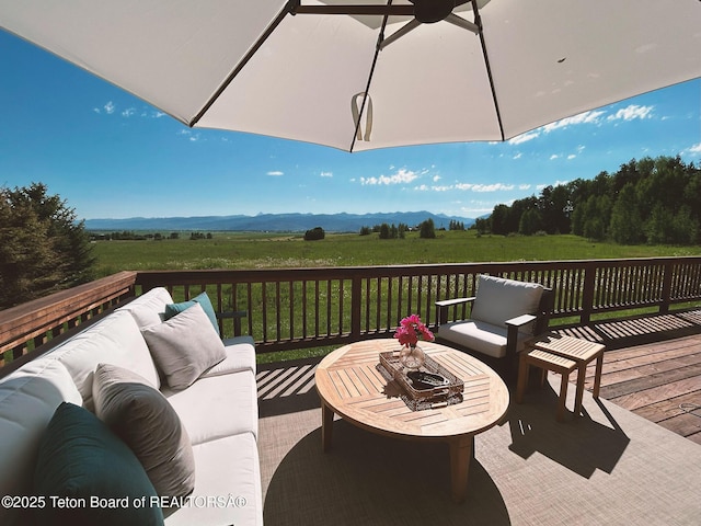 wooden terrace with an outdoor hangout area, a mountain view, and a rural view