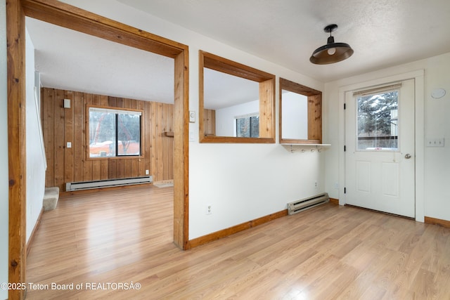 foyer with a baseboard radiator, plenty of natural light, and light wood-type flooring