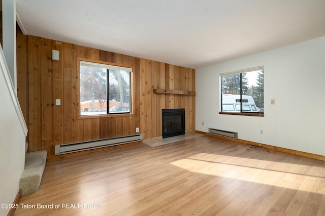 unfurnished living room with a baseboard radiator, light hardwood / wood-style floors, and wood walls