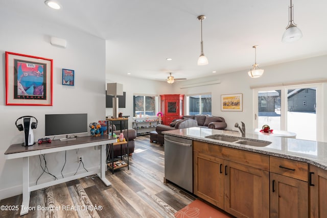 kitchen with dark hardwood / wood-style floors, decorative light fixtures, sink, stainless steel dishwasher, and light stone countertops