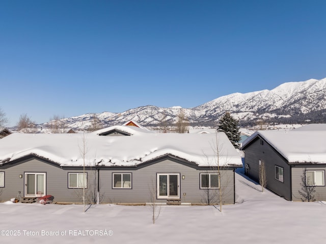 snow covered rear of property with a mountain view