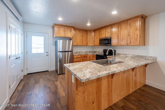 kitchen with dark wood-type flooring, sink, a textured ceiling, stainless steel refrigerator, and black / electric stove