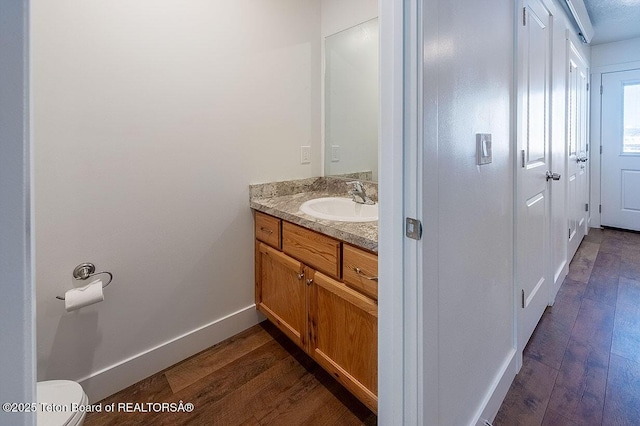 bathroom featuring wood-type flooring, vanity, and toilet