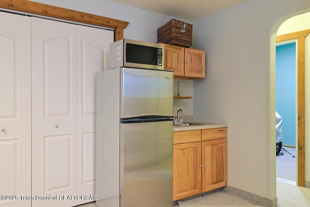 kitchen with stainless steel fridge, sink, and light carpet