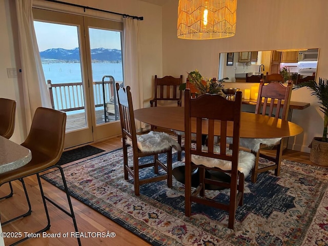 dining room with hardwood / wood-style flooring and a water and mountain view