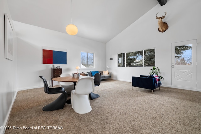 carpeted dining room with beam ceiling and high vaulted ceiling