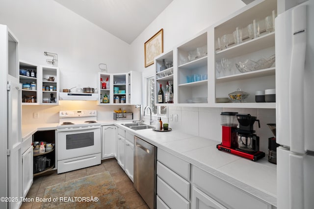 kitchen featuring vaulted ceiling, sink, white cabinets, tile counters, and white appliances