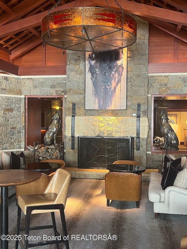 living room with a stone fireplace, high vaulted ceiling, and beam ceiling