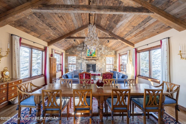 dining area featuring beamed ceiling, wood ceiling, a fireplace, and hardwood / wood-style floors