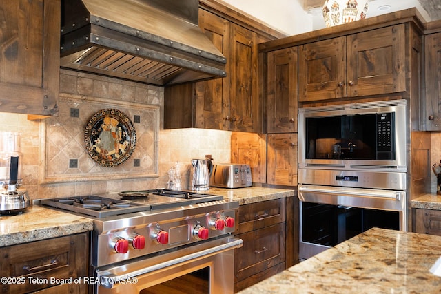 kitchen with light stone counters, stainless steel appliances, extractor fan, and tasteful backsplash