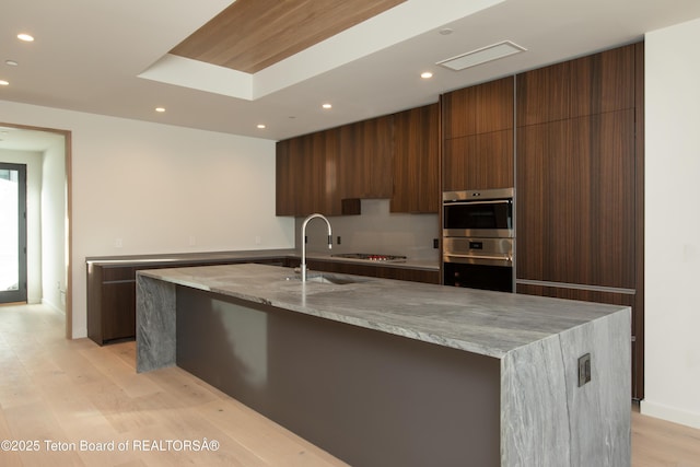 kitchen featuring light stone counters, sink, a spacious island, and appliances with stainless steel finishes