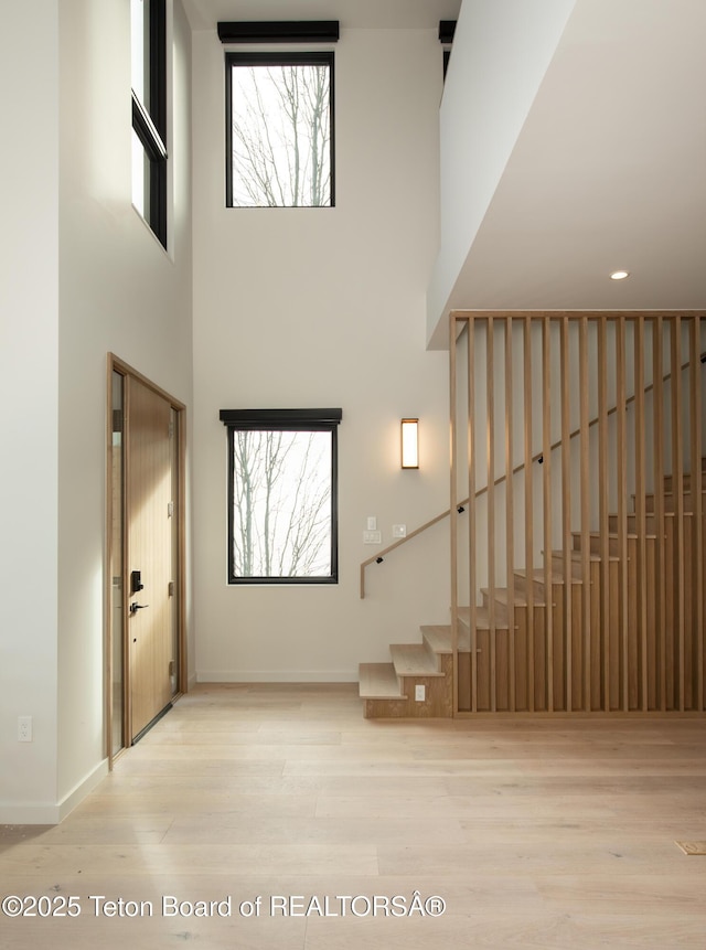 stairway featuring hardwood / wood-style flooring, a towering ceiling, and plenty of natural light