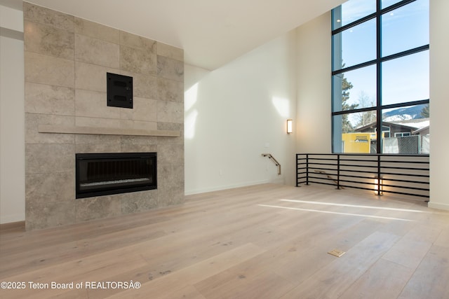 unfurnished living room with a tiled fireplace and hardwood / wood-style floors