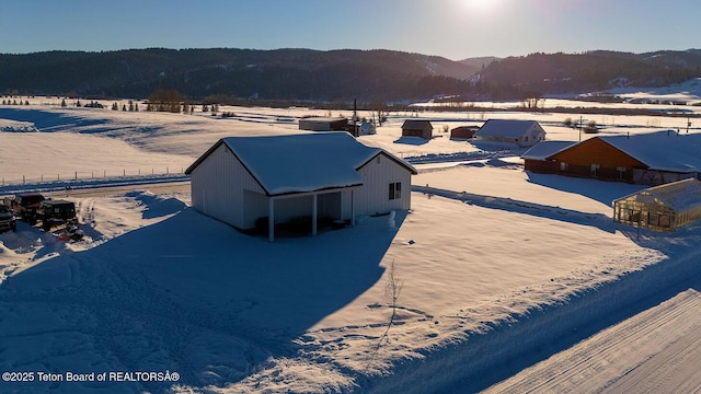 snowy aerial view featuring a mountain view and a rural view