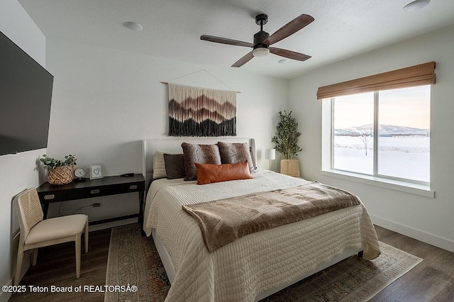 bedroom featuring dark wood-type flooring, ceiling fan, and a mountain view