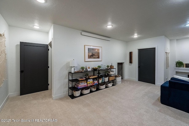 interior space with a wall unit AC, light colored carpet, and a textured ceiling