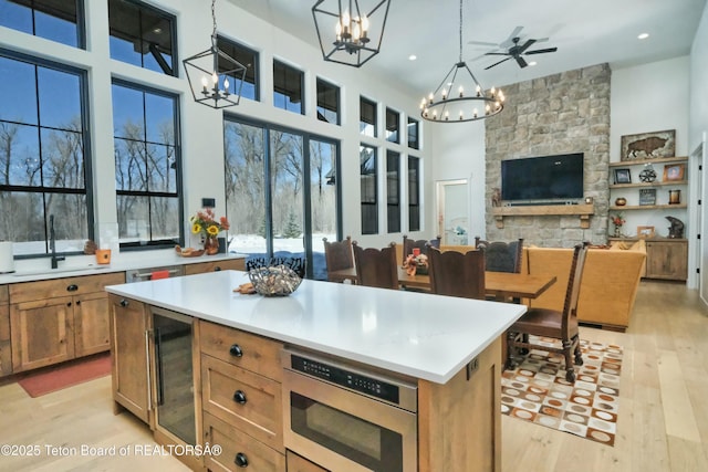 kitchen featuring a center island, stainless steel microwave, decorative light fixtures, beverage cooler, and a chandelier