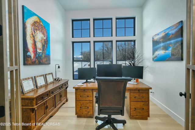 office area featuring light hardwood / wood-style flooring and a high ceiling