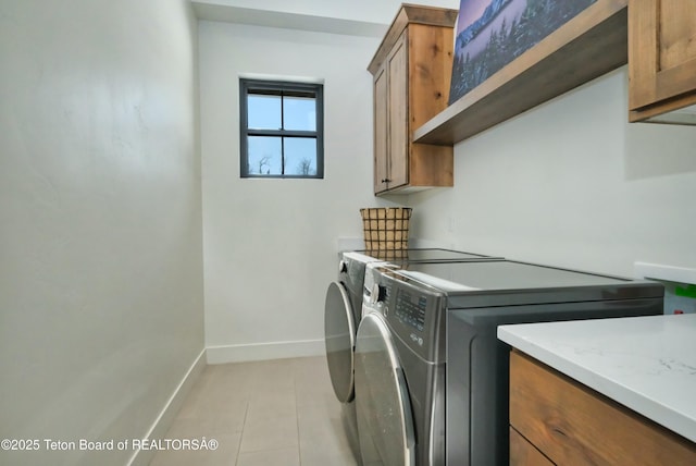 laundry room with cabinets, light tile patterned flooring, and independent washer and dryer