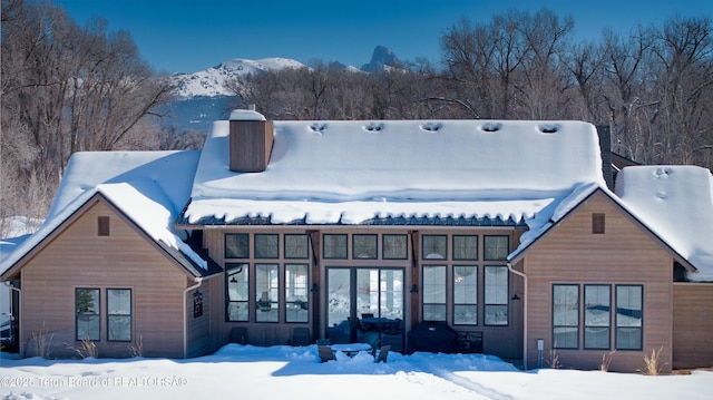 snow covered back of property with a mountain view