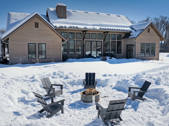 snow covered house with an outdoor fire pit