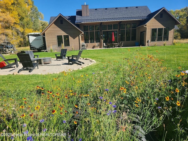 back of house featuring a yard, a patio area, and an outdoor fire pit