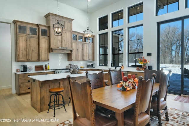 dining space with a towering ceiling, light hardwood / wood-style floors, and a chandelier