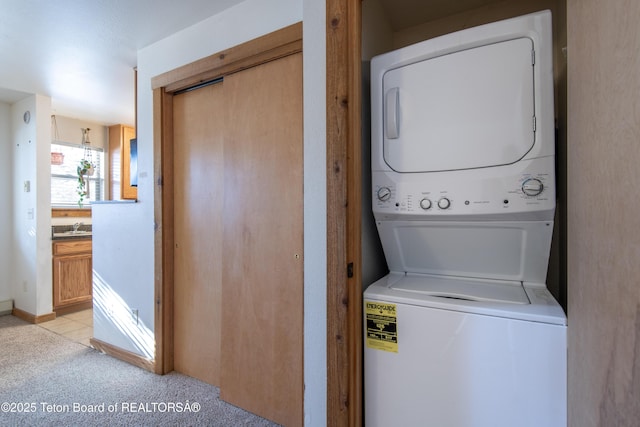 laundry room with sink, light colored carpet, and stacked washer / dryer