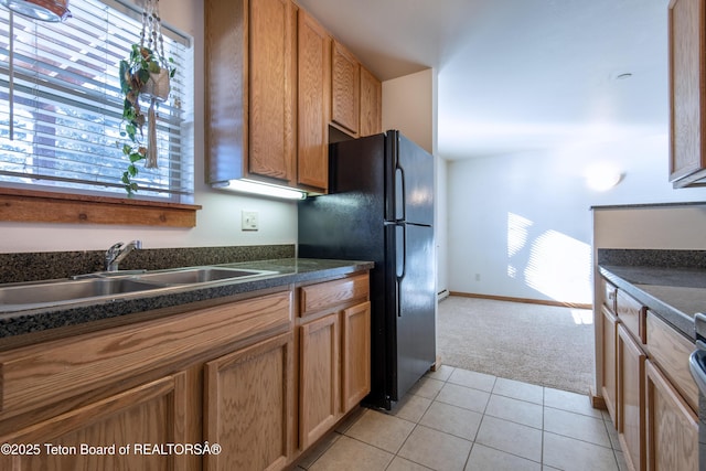 kitchen with black fridge, sink, and light tile patterned floors