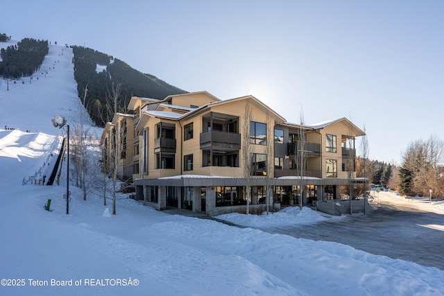 snow covered rear of property with a mountain view