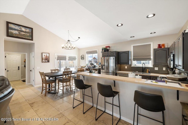 kitchen featuring lofted ceiling, sink, stainless steel appliances, a kitchen breakfast bar, and a healthy amount of sunlight