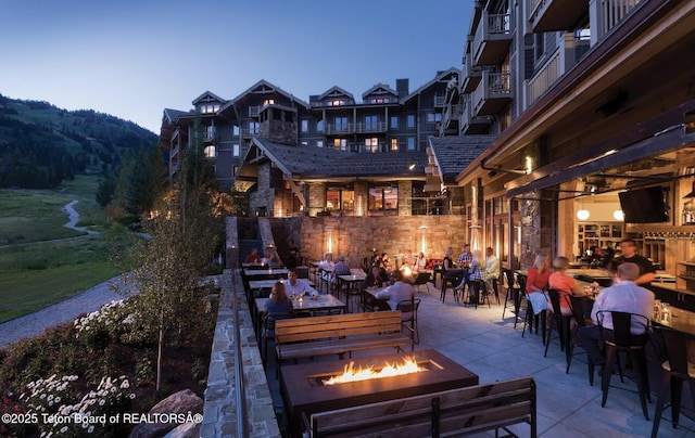 patio terrace at dusk with a mountain view and an outdoor fire pit