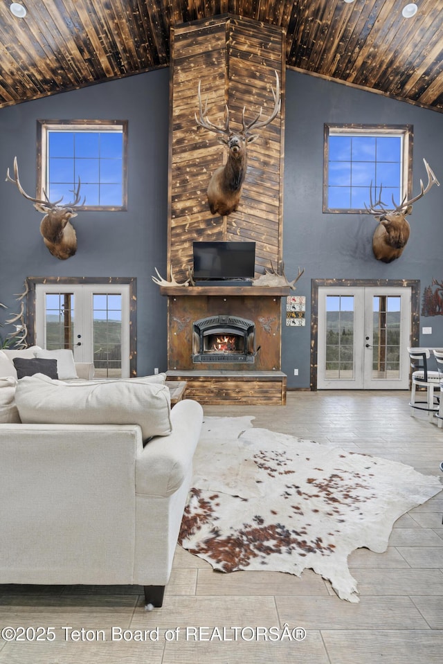 living room featuring high vaulted ceiling, a fireplace, and french doors