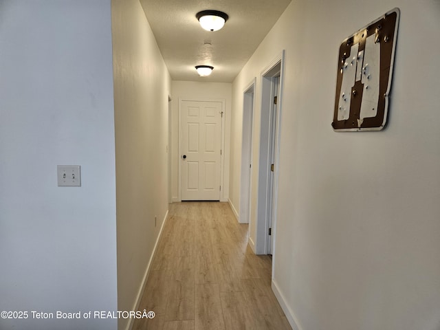 hall featuring a textured ceiling and light hardwood / wood-style flooring