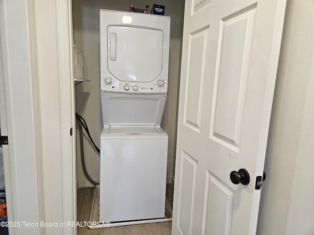 clothes washing area featuring stacked washer / dryer and light hardwood / wood-style floors