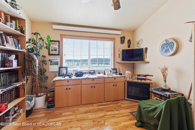 kitchen featuring ceiling fan, lofted ceiling, a textured ceiling, and light wood-type flooring