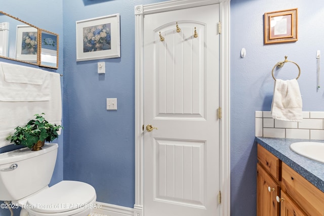 bathroom featuring vanity, backsplash, and toilet