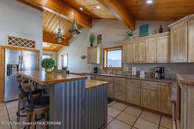 kitchen featuring stainless steel appliances, butcher block counters, sink, and light brown cabinets