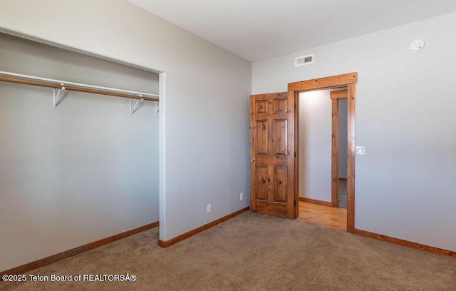 unfurnished bedroom with light carpet and a closet